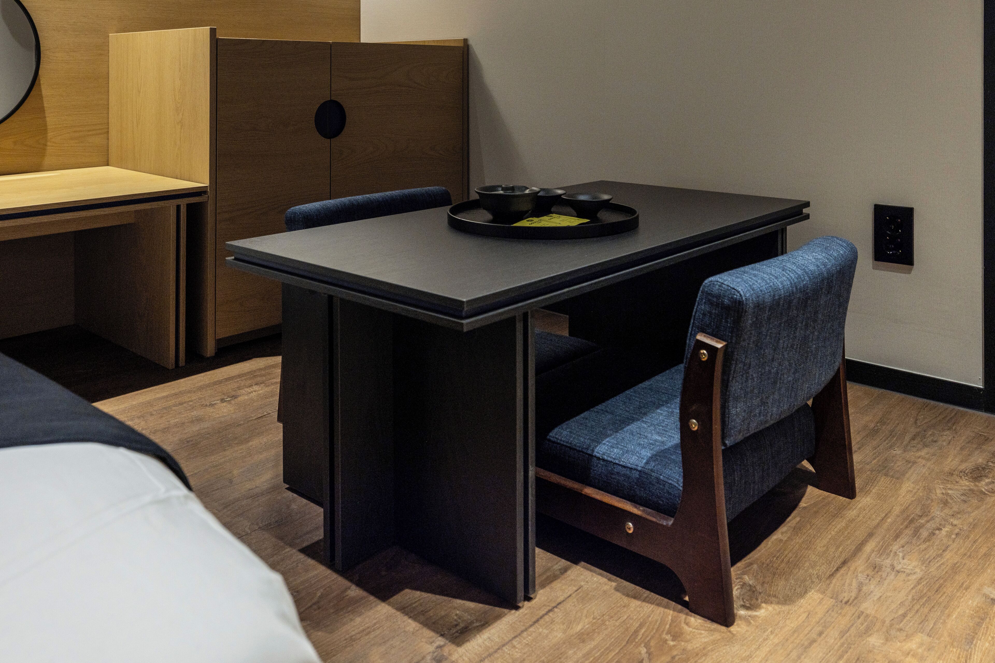 Habitación compacta con una mesa plegable, dos sillas, una mesita redonda con bandeja y un separador de madera.