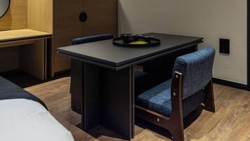 Habitación compacta con una mesa plegable, dos sillas, una mesita redonda con bandeja y un separador de madera.