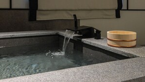 A stone-floored hot spring with a black faucet and a wooden bowl on the right. - mitasuyaryokanhotel by anook gangneung (Gangneung)