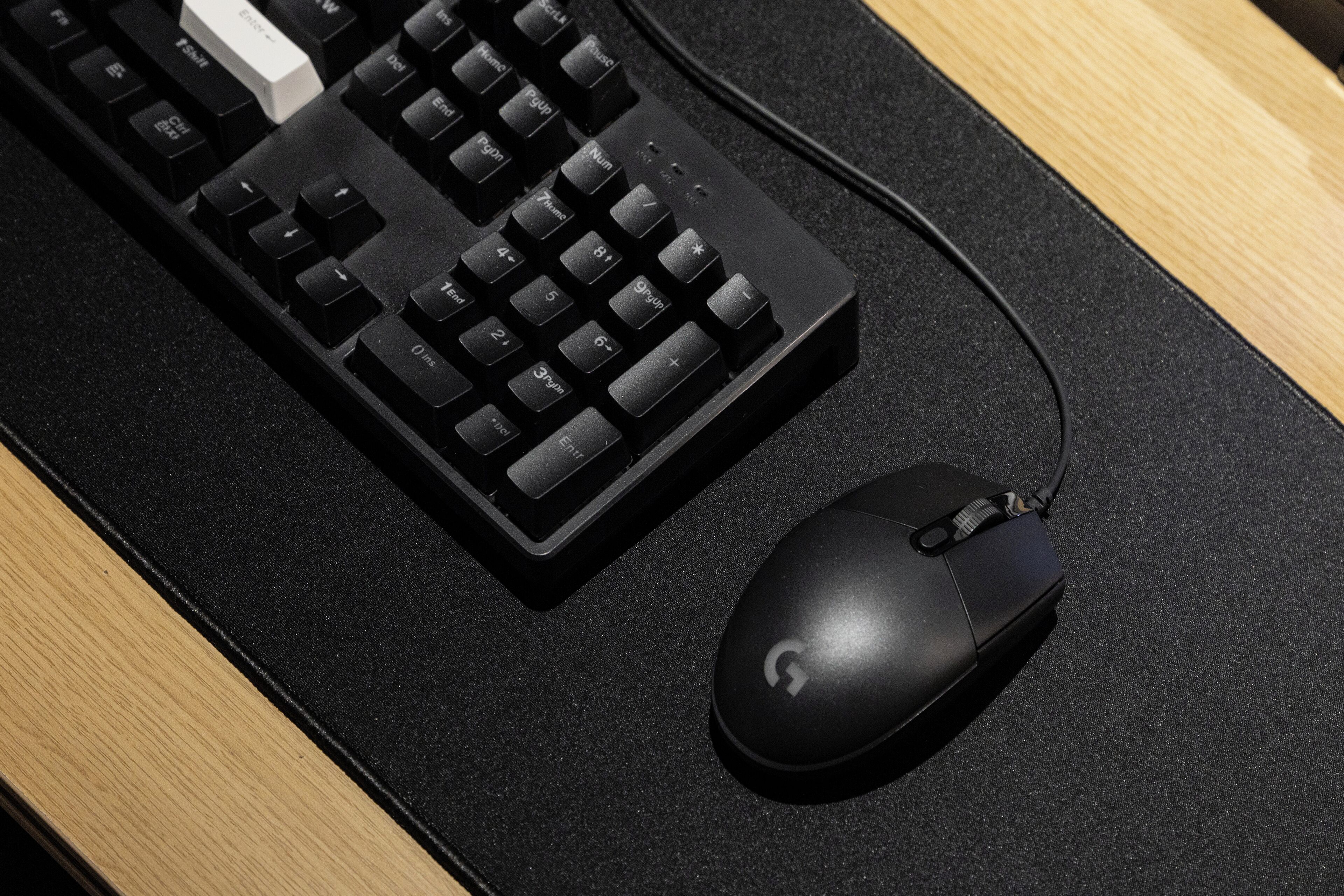 A black keyboard and mouse on a black mouse pad.