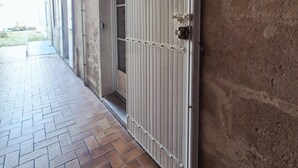 Un couloir avec un sol carrelé, une grille métallique et un mur en béton.