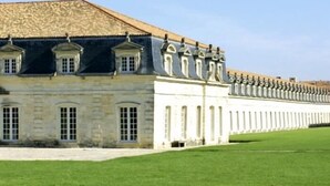 Un long bâtiment blanc, doté d’une façade symétrique et d’une série de fenêtres.