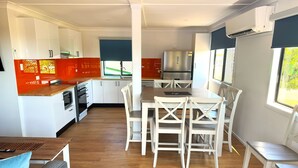 A modern kitchen with white cabinets, a wooden countertop, and a stainless steel refrigerator. - 3 Bedroom, 2 Bathroom Holiday House (Karumba)