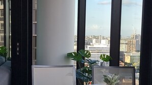 A balcony with a table and chairs, a potted plant, and a city view. - Skyline Apartment in Fortitude Valley (Fortitude Valley)