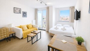 Una habitación de hotel moderna con sofá, una mesita, cama y televisor.