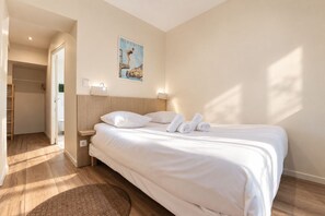 Ein Hotelzimmer mit einem Bett, einem Nachttisch, einer Wandleuchte, einem Bild und Holzböden.