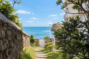 A stone pathway leading to a coastal view with a clear sky and a rocky cliff. - Beachfront Apartment with Terrace, Biarritz (Biarritz)