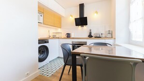 Een compacte keuken met een wasmachine, een eettafel met stoelen en een raam dat voor natuurlijk licht zorgt.