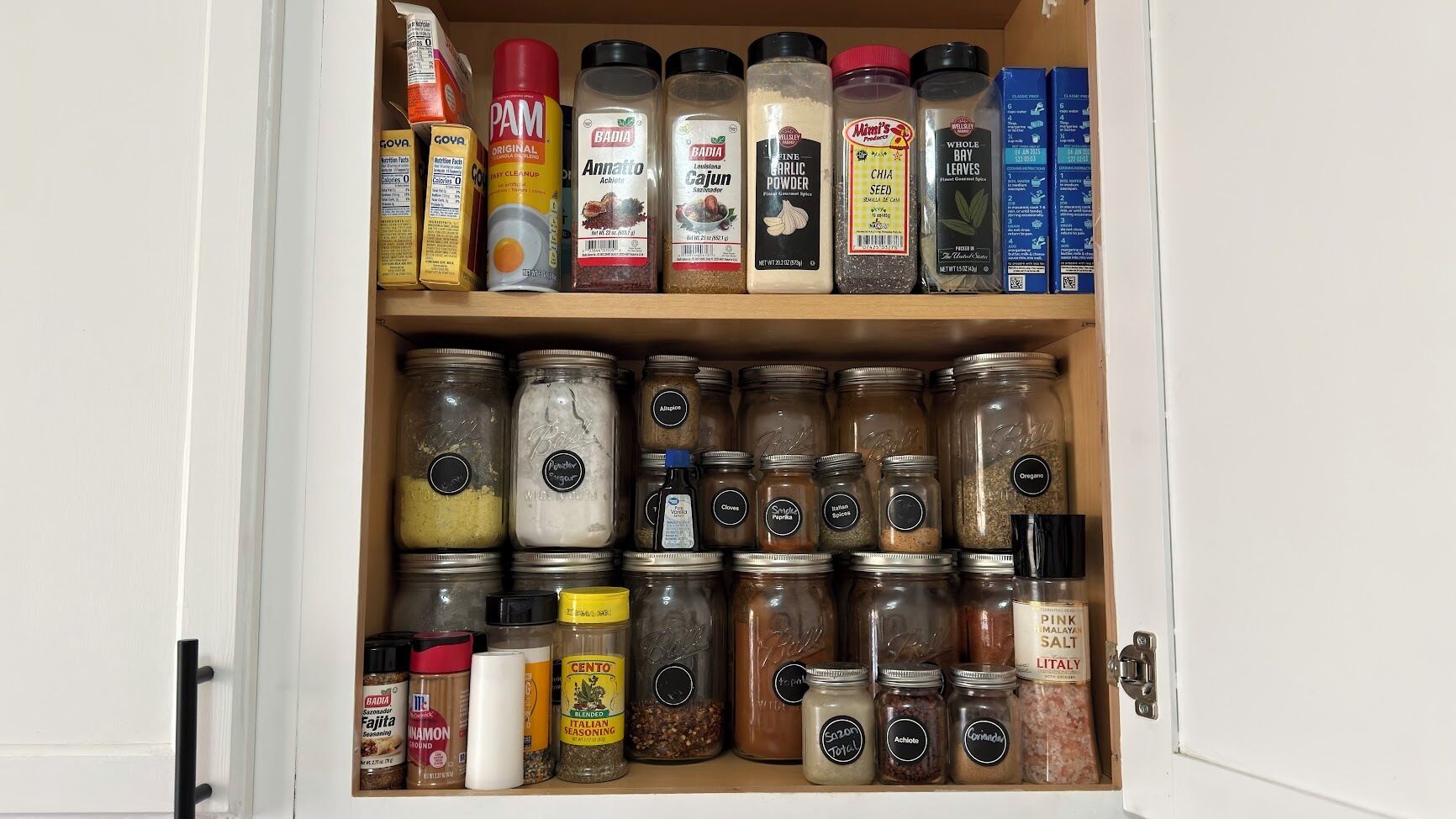 Un garde-manger contenant diverses épices et assaisonnements, notamment des marques comme PAM, BADIA et CENTO.