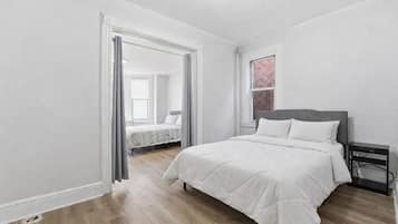 Une chambre à coucher avec un lit, une table de chevet et une fenêtre ornée d’un motif rose.