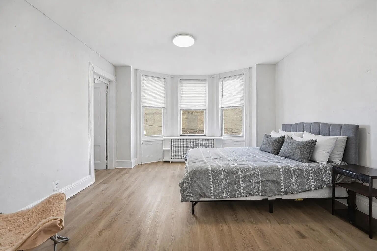 Een slaapkamer met een bed, een raam en een radiator.