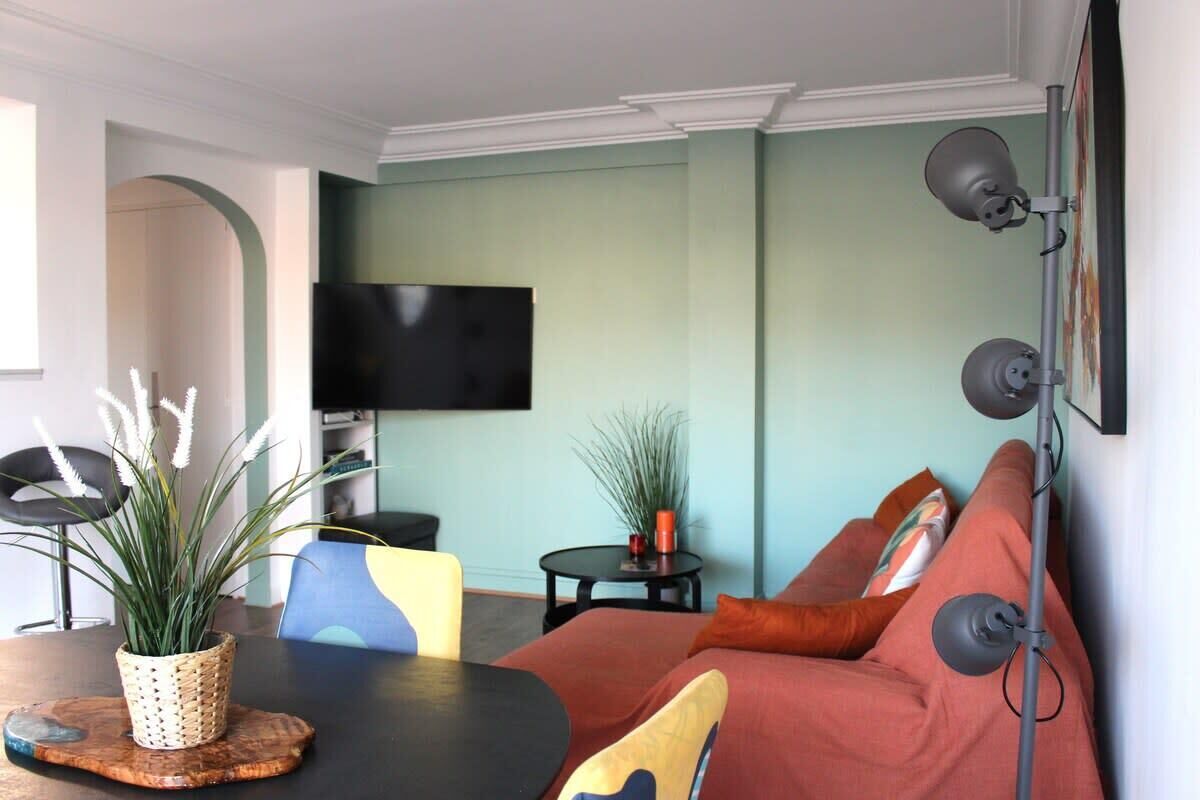 Un salon avec un canapé, un téléviseur, une plante et une table.