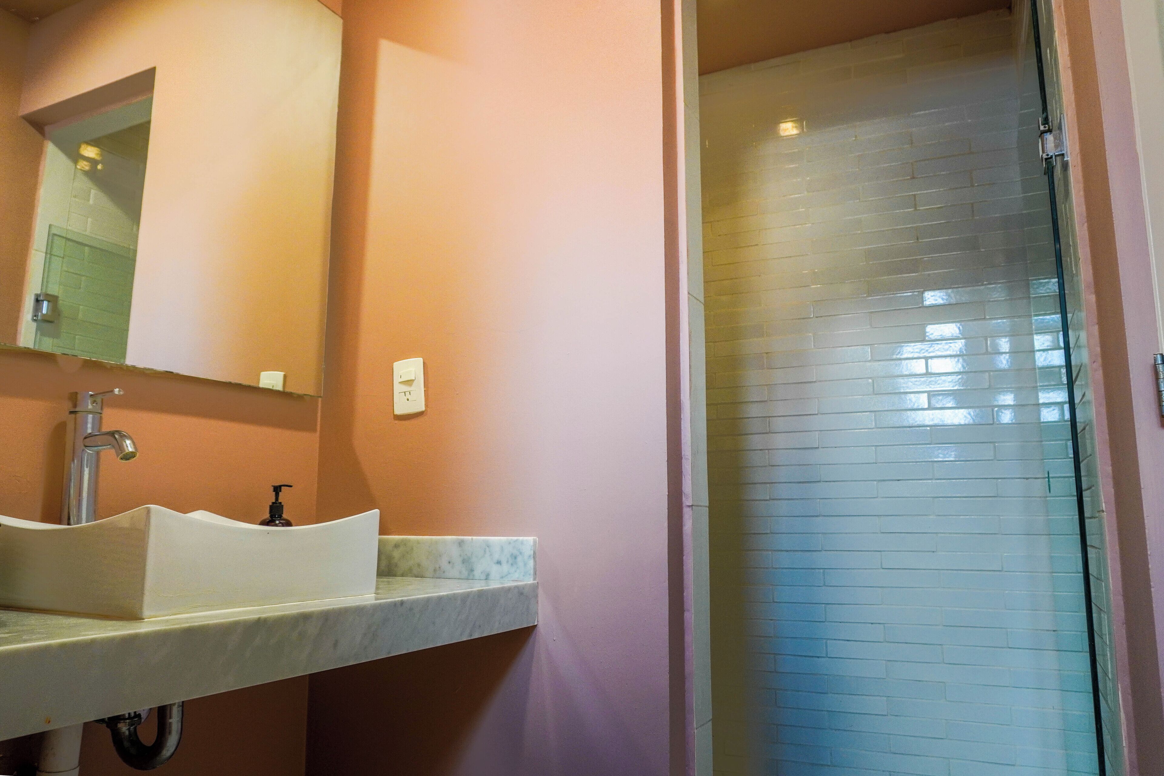A bathroom with a sink, mirror, and shower.