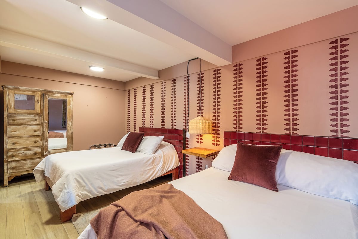 Une chambre d’hôtel avec deux lits, une armoire en bois et un mur décoré de motifs.