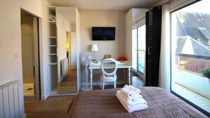 Une chambre à coucher avec un lit, un bureau, une chaise, une télévision et une fenêtre donnant sur un beau paysage.