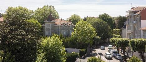 Vista de una calle con edificios, árboles y coches aparcados.