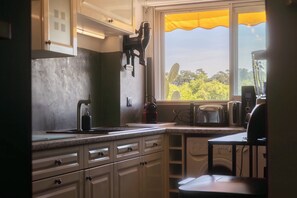 A kitchen with a window, a toaster, a kettle, and a coffee maker. - Cosy apartment with Balcony near the Beach (Biarritz)