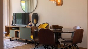 A dining area with a round table, chairs, a mirror, and pendant lighting. - Cosy apartment with Balcony near the Beach (Biarritz)