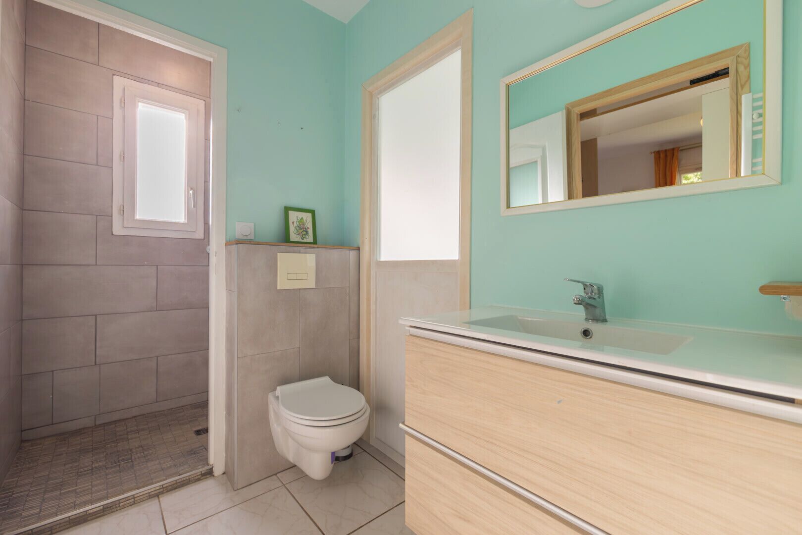 A bathroom with a shower, toilet, vanity, and a mirror.