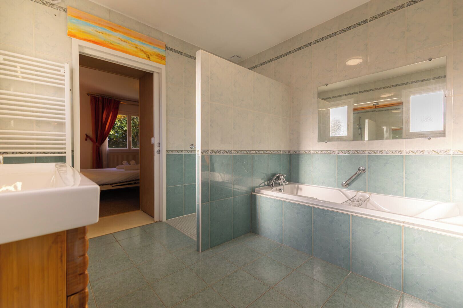 Ein Badezimmer mit Badewanne, Dusche und einem Fenster mit Vorhängen.