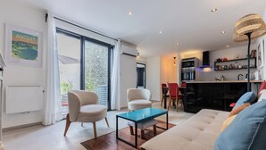 Una sala de estar moderna con un sofá, dos sillones, una mesa de centro y una zona de comedor con sillas.