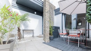 Un patio al aire libre con una mesa, sillas, una planta en maceta y un pilar de piedra.