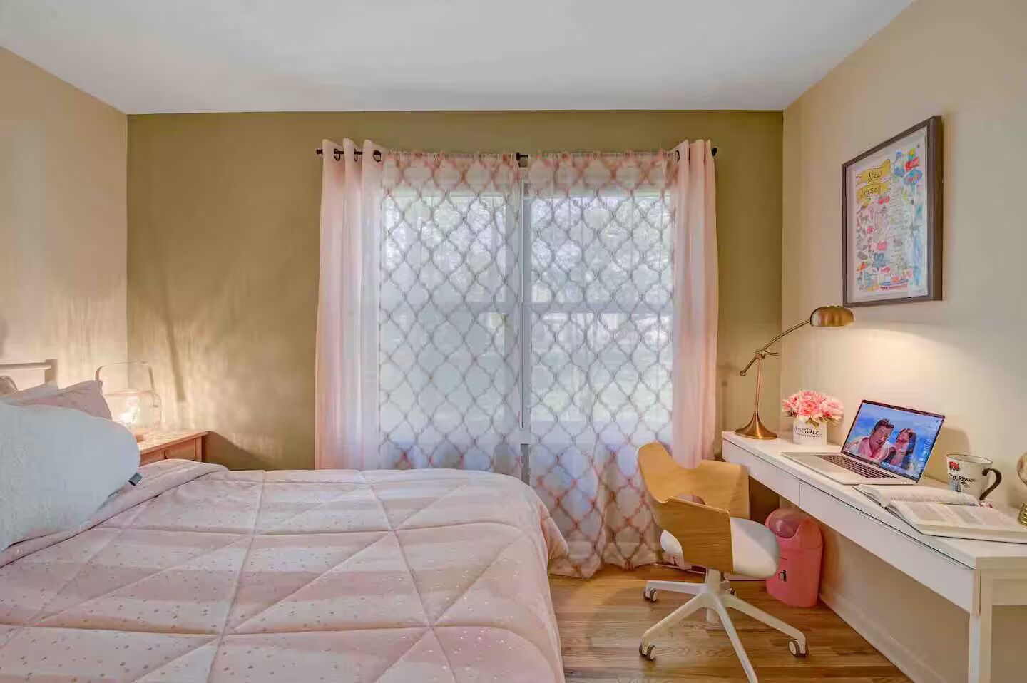 Une chambre à coucher avec un lit, un bureau avec un ordinateur portable, une chaise et une fenêtre avec des rideaux.