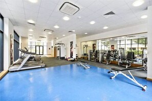 Une salle de sport équipée de tapis de course, d’appareils de musculation et dotée d’un sol bleu.