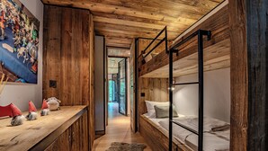 A wooden interior with bunk beds, a wooden desk, and a fur rug. - Rochebrune (Megève)
