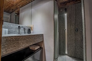 Un baño con encimera de granito, un espejo, una toalla y cabina de ducha.