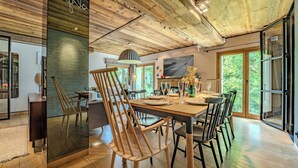 A dining area with a wooden table, chairs, and a TV mounted on the wall. - Rochebrune (Megève)