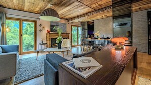 A modern interior with a wooden ceiling, a fireplace, a dining area, and a bar. - Rochebrune (Megève)