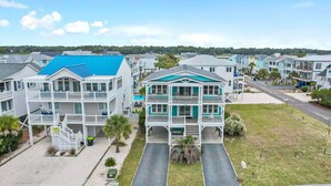 A coastal residential area with multi-story houses featuring balconies, a clear sky, and a road in the foreground. - "2ice As Nice" - 4 Bedrooms, 3.5 Bathrooms, Private Pool (Holden Beach)