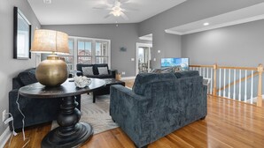 A living room with a dark grey sofa, a round coffee table with a lamp, and a ceiling fan. - "2ice As Nice" - 4 Bedrooms, 3.5 Bathrooms, Private Pool (Holden Beach)