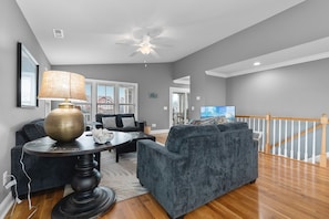 A living room with a dark grey sofa, a round coffee table with a lamp, and a ceiling fan. - "2ice As Nice" - 4 Bedrooms, 3.5 Bathrooms, Private Pool (Holden Beach)
