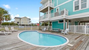 A wooden deck with a swimming pool, white fences, and a two-story building with balconies. - "2ice As Nice" - 4 Bedrooms, 3.5 Bathrooms, Private Pool (Holden Beach)