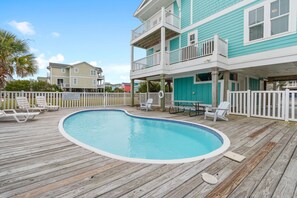 A wooden deck with a swimming pool, white fences, and a two-story building with balconies. - "2ice As Nice" - 4 Bedrooms, 3.5 Bathrooms, Private Pool (Holden Beach)