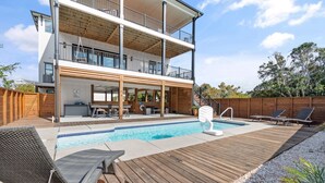 A two-story building with a swimming pool, outdoor seating, and a wooden deck. - 5 Bedrooms, 5 Bathrooms, Private Pool (Holden Beach)