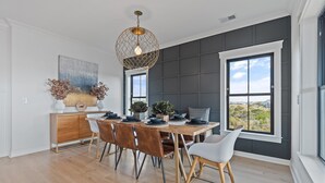 A dining area with a wooden table, chairs, a decorative light fixture, and a view through large windows. - 5 Bedrooms, 5 Bathrooms, Private Pool (Holden Beach)