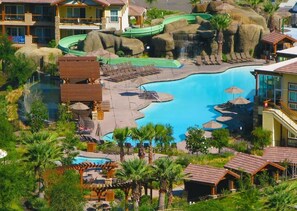 Um resort com uma piscina grande, um toboágua e vários edifícios com varandas.