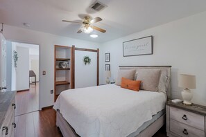 Ein Schlafzimmer mit Bett, Nachttisch und Deckenventilator.