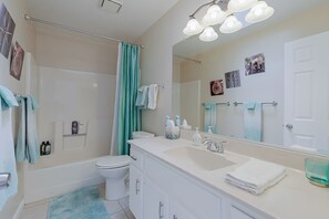 Ein modernes Badezimmer mit einer Badewanne, Toilette, Waschbecken und einem großen Spiegel.
