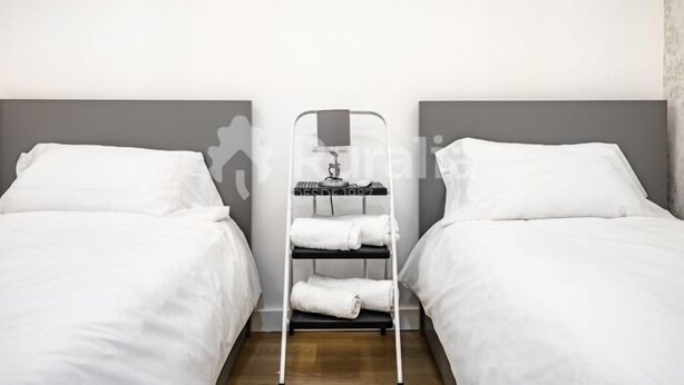Una habitación de hotel con dos camas, un escurridor de metal con toallas y un espejo.