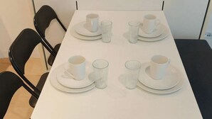 A square table with four white plates and cups, surrounded by four black chairs. - Cozy apartment canal view (Amsterdam)