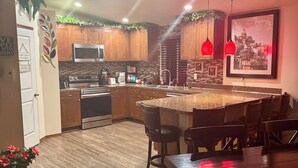 A modern kitchen with wooden cabinets, a central island, and pendant lighting. - Large 6BR with Game Room, Perfect for Large Families & Groups, Forks PNW Retreat (Forks)