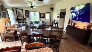A living room with a dining area, a ceiling fan, a flat-screen TV, and a fireplace. - Large 6BR with Game Room, Perfect for Large Families & Groups, Forks PNW Retreat (Forks)