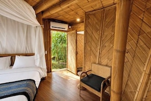 A room with a bed, a chair, and a view of greenery outside. - Asep Gumi Bamboo Villa Pesagi (Bali)