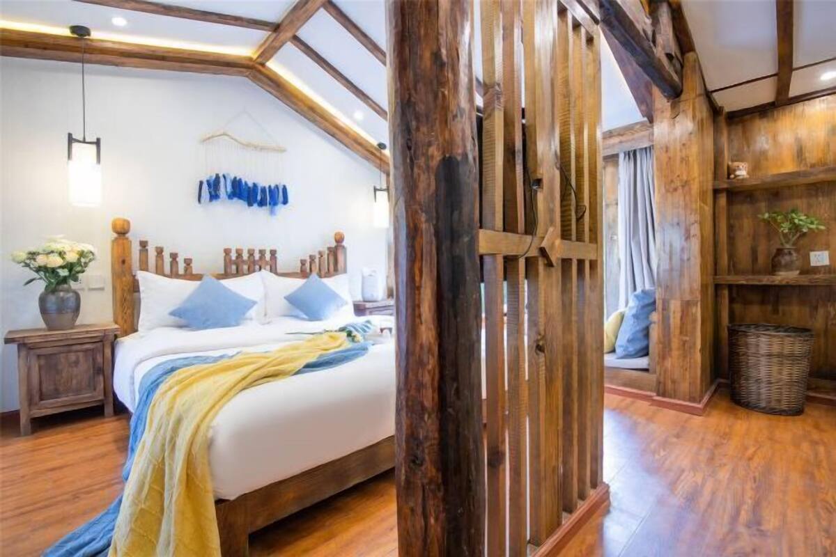A room with a wooden bed, a hanging light fixture, a wooden wall, and a basket.