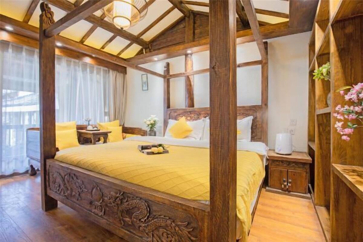 A four-poster bed with a wooden headboard, a bedside table, a nightstand, and a small cabinet.