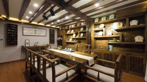 A traditional Japanese-style room with a wooden dining table, benches, and shelves with clocks and decorative items. - ‌The Secret Garden of Cats & Wolf's Den Barista Courtyard Cafe & Inn (Wuyi Street) (Lijiang)